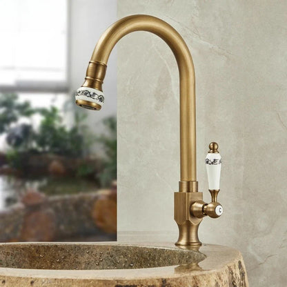 Antique brass single hole outdoor antifreeze faucet with curved swivel spout and ceramic black floral handle accents