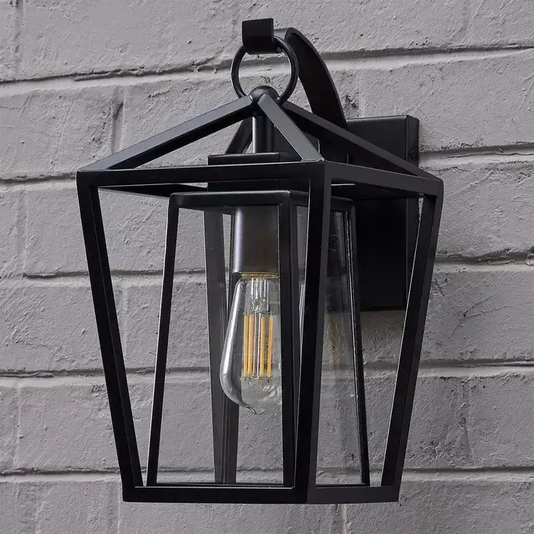 Black wrought iron outdoor wall light with clear glass shades and visible filament bulb by DecorBites™