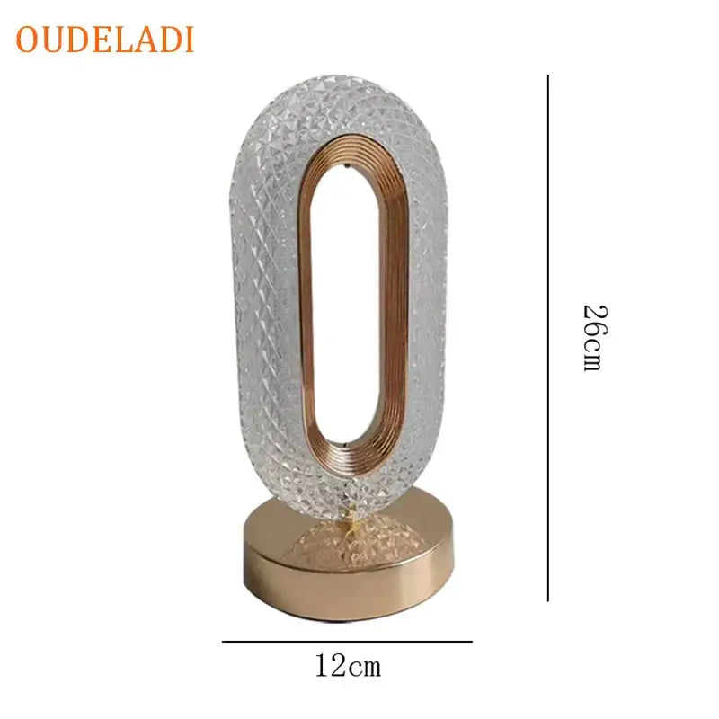 A sleek crystal bedroom table lamp with a diamond-cut clear body and a gold oval frame for decorbites atmosphere light