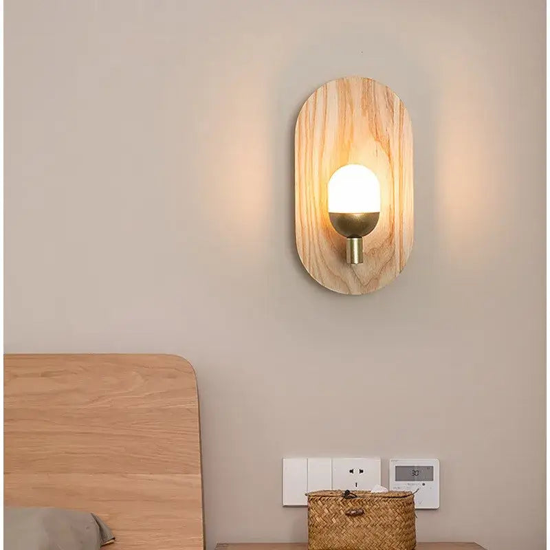Warm-toned oval led wooden wall lamp with brass base and frosted glass bulb by decorbites for bedroom decor