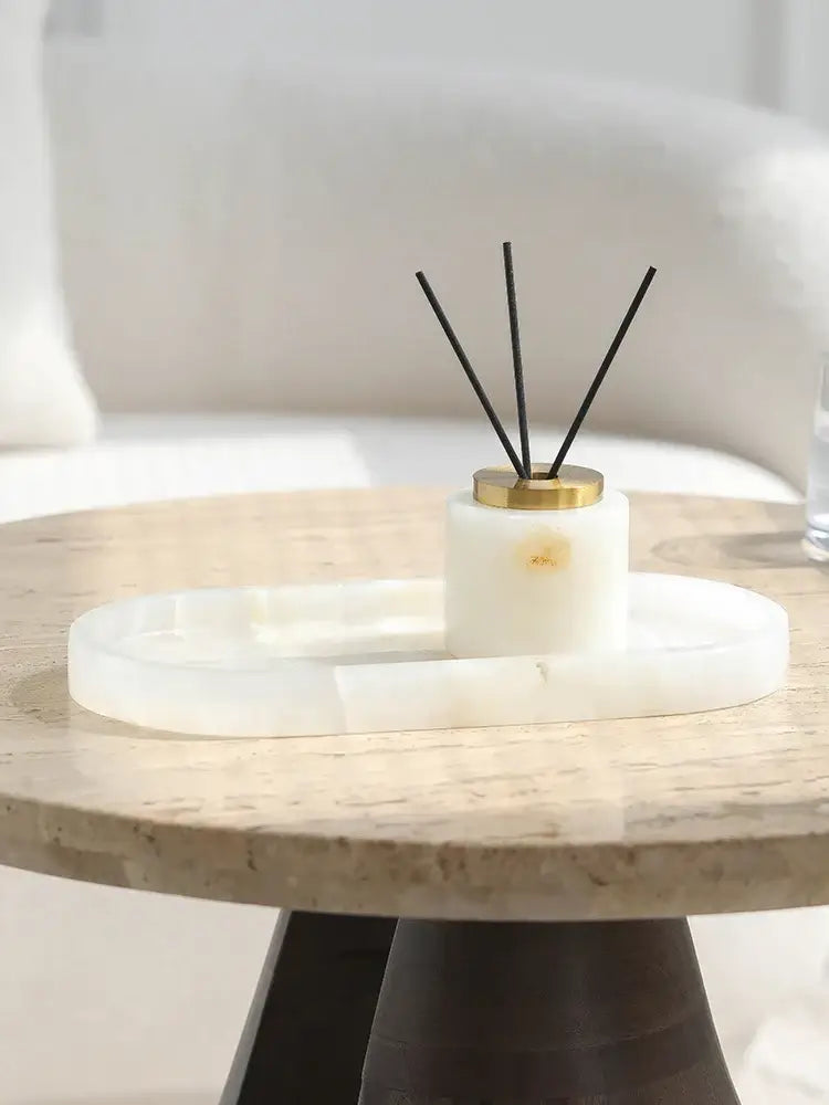 White cylindrical reed diffuser with gold cap and black reeds on oval white decorbites calacatta marble vanity tray