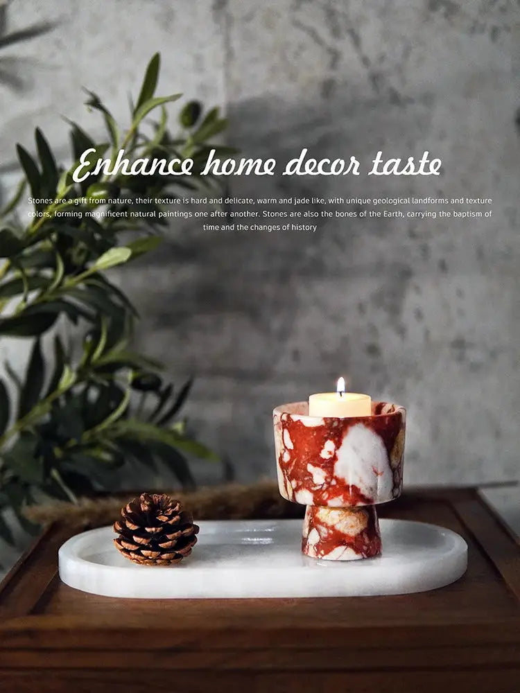 A red and white marbled stone candle holder with a lit candle on a decorbites calacatta marble vanity tray soap dish