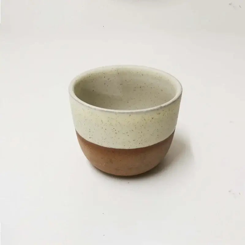 A ceramic tea cup from a pastel and terracotta cup set with off-white speckled glaze and earthy brown clay finish