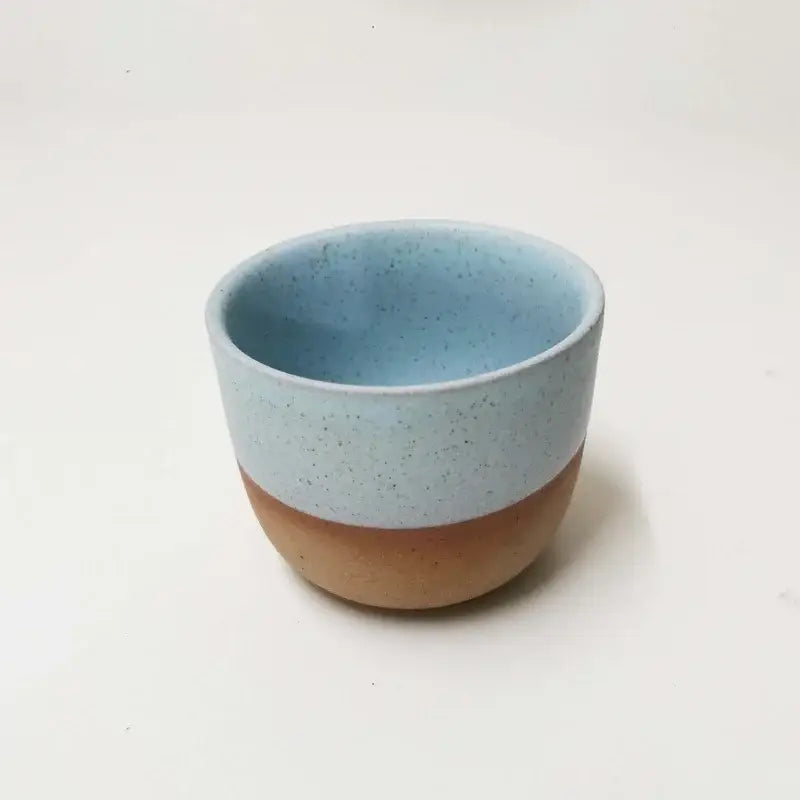 A handcrafted pastel and terracotta ceramic tea cup set featuring a speckled light blue and smooth terracotta design