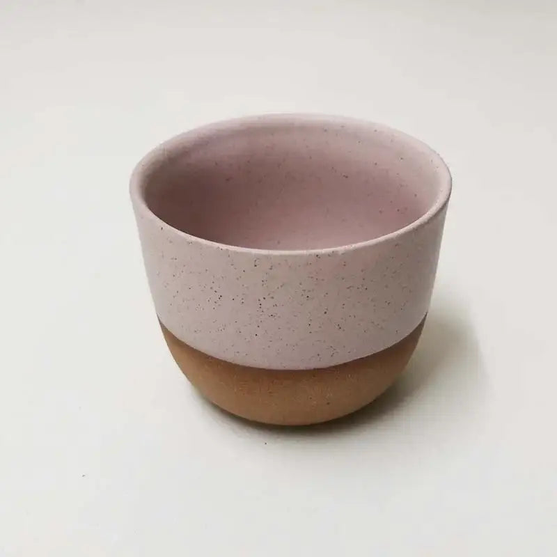 A blush pink speckled ceramic tea cup with a terracotta base from a pastel and terracotta cup set