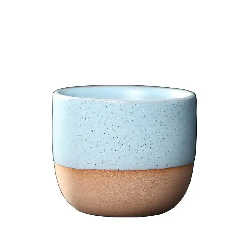 A ceramic tea cup set featuring a speckled light blue upper half and smooth earthy brown lower half for dining use