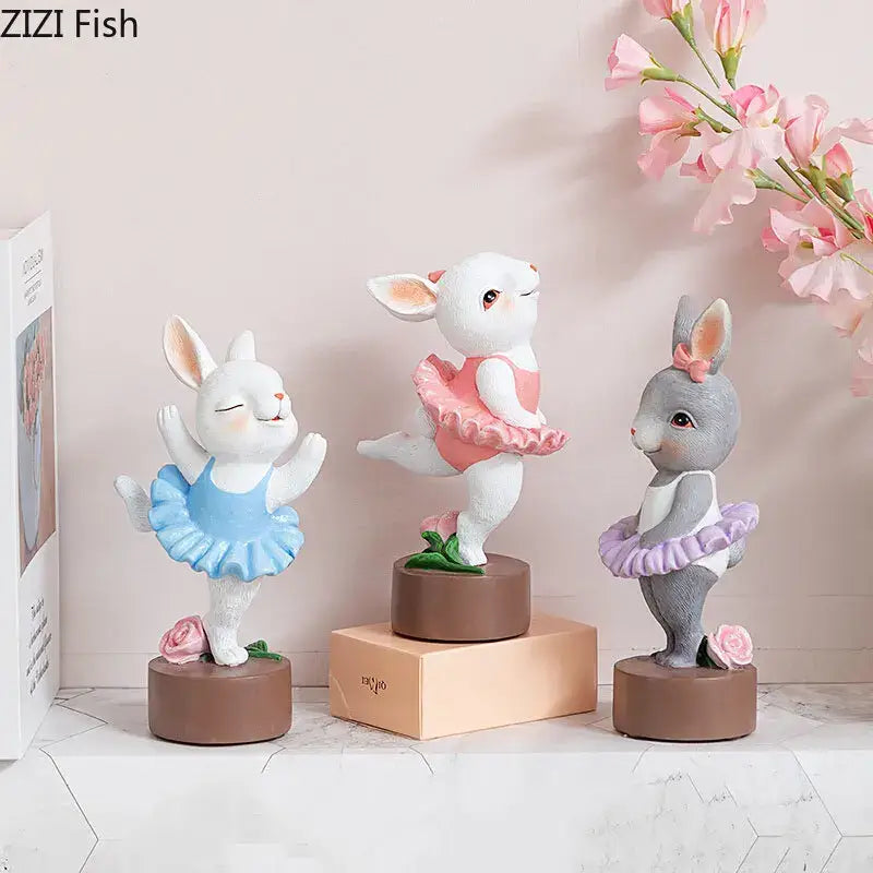 Three resin pastel ballet rabbit dancer sculptures in blue pink and purple tutus with floral bases for desk decor