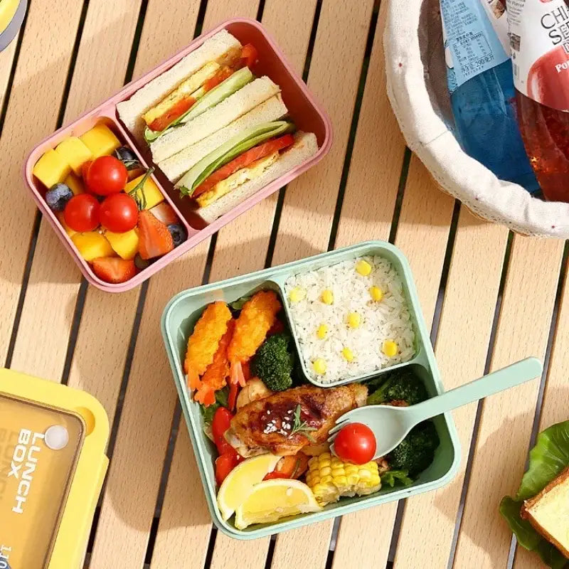 Pastel green rectangular decorbites bento box set with three compartments filled with rice grilled chicken vegetables and lemon wedge