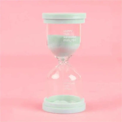 A mint green plastic-capped glass sand timer with printed text from a pastel blue and pink sand timer set for kids bedroom decor