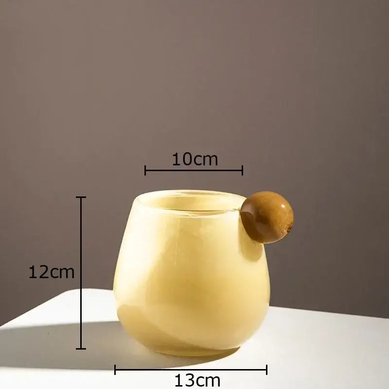 A pale yellow translucent glass vase with a rounded body and wooden ball handle for colorful glass decor