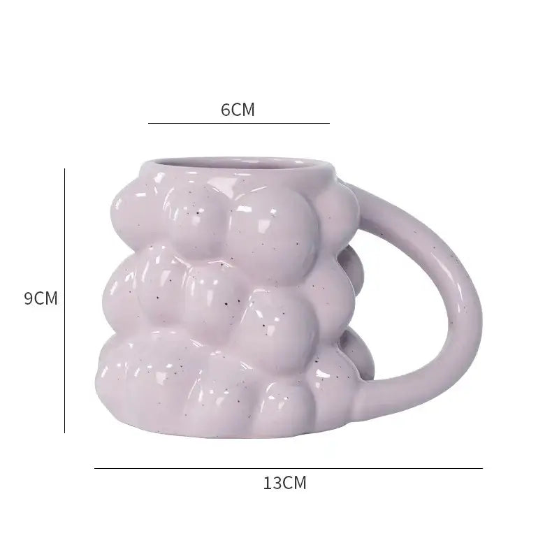 A matte lavender pastel bubbly grape ceramic mug with textured bubble surface and speckled finish for kitchen use