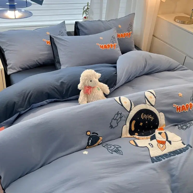 Blue cartoon embroidered cotton bedding set featuring astronaut theme with embroidered details and orange happy text from decorbites