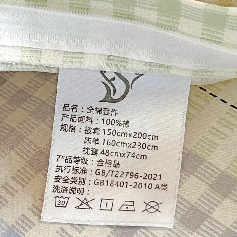 White fabric label with black Chinese text attached to a pastel checkered cotton printed student bedding set decorbites cotton printed