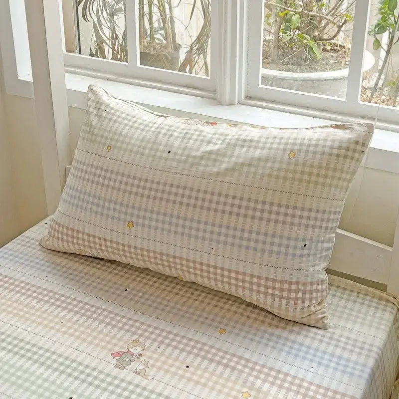 A cream-colored soft pillow with beige white gingham and embroidered stars in a pastel checkered cotton printed bedding set