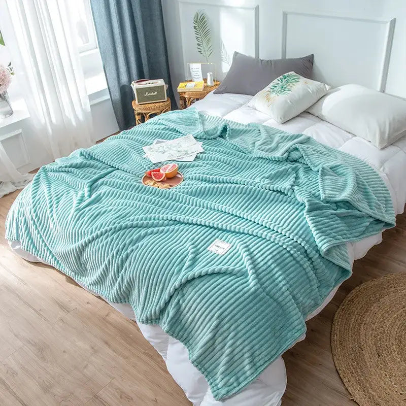A soft mint green corduroy cozy hug blanket with ribbed texture draped over a bed for decorbites cozy hug use