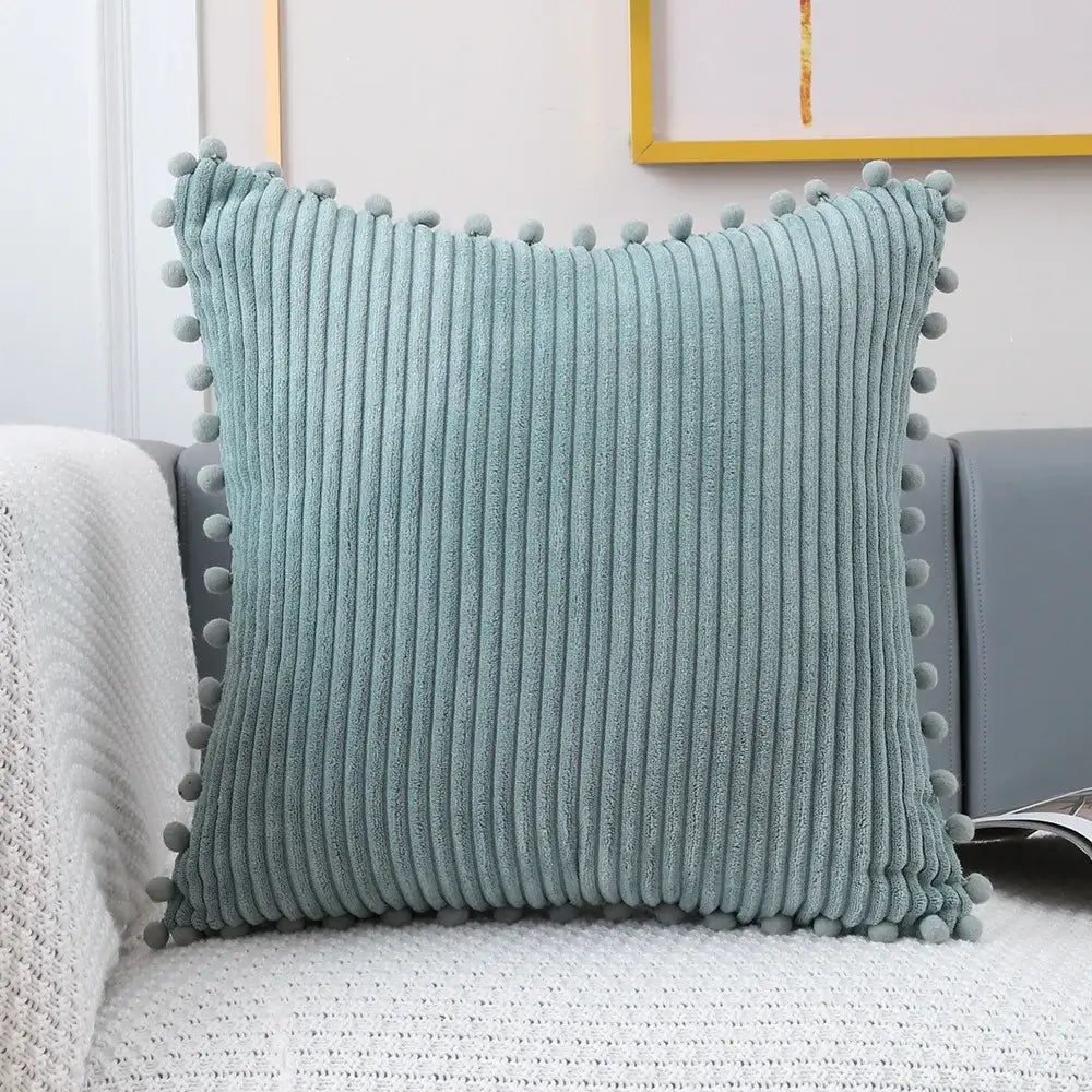 A soft teal corduroy pompom cushion cover with textured vertical ribs and decorative gray pom-poms for living room decor