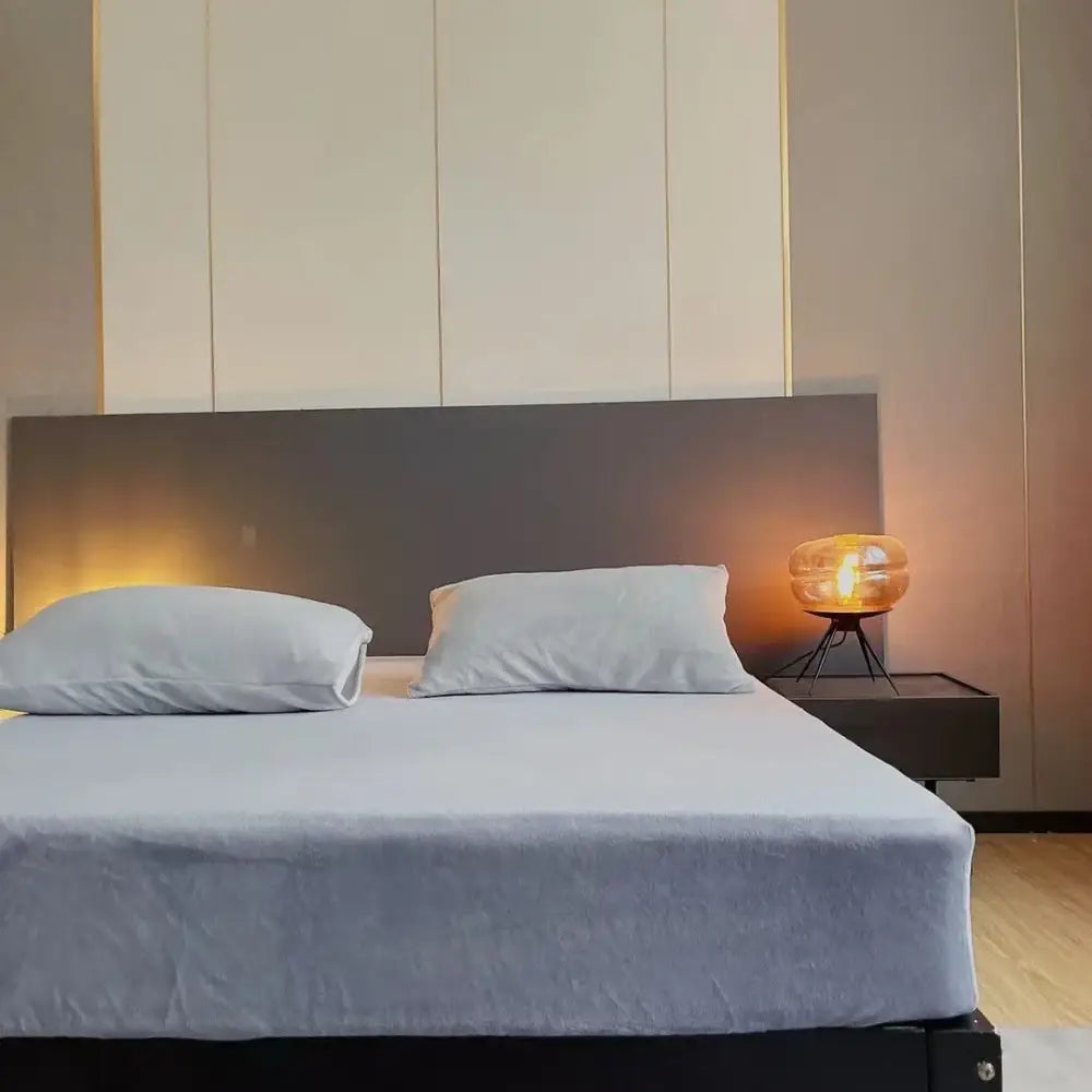 Modern minimalist bedside table with black finish and amber glass orb lamp in a pastel cozy flannel queen bed sheet bedroom decorbites cozy flannel