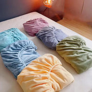 Six pastel cozy flannel queen bed sheets in soft blue pink lavender yellow and green neatly arranged on white surface