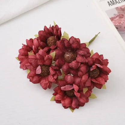 Cluster of artificial maroon paper flowers with glittery brown centers and green leaves in decorbites daisy sunflower bouquet