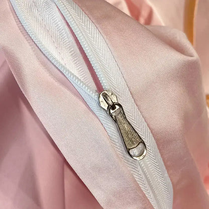 A white zipper with silver pull tab on soft pink satin fabric in pastel decorbites embroidered butterfly bedding set