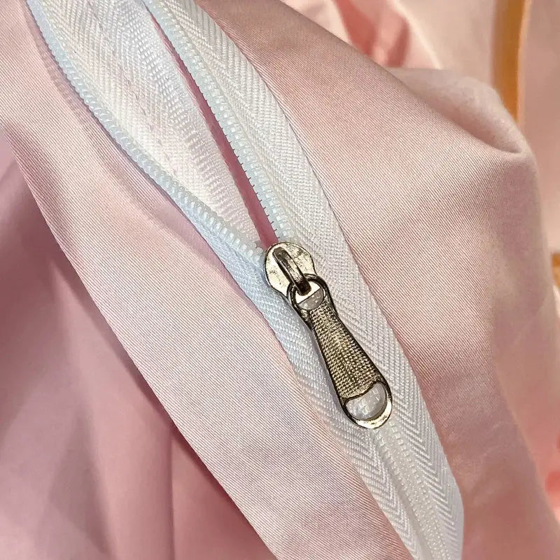 A white zipper with silver pull tab on soft pink satin fabric in pastel decorbites embroidered butterfly bedding set