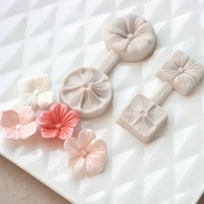 Set of delicate pastel-colored silicone five petals flower molds with intricate petal designs and matching crafted flowers
