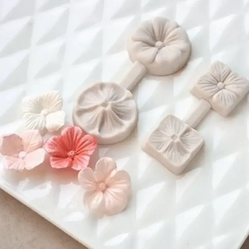 Set of delicate pastel-colored silicone five petals flower molds with intricate petal designs and matching crafted flowers
