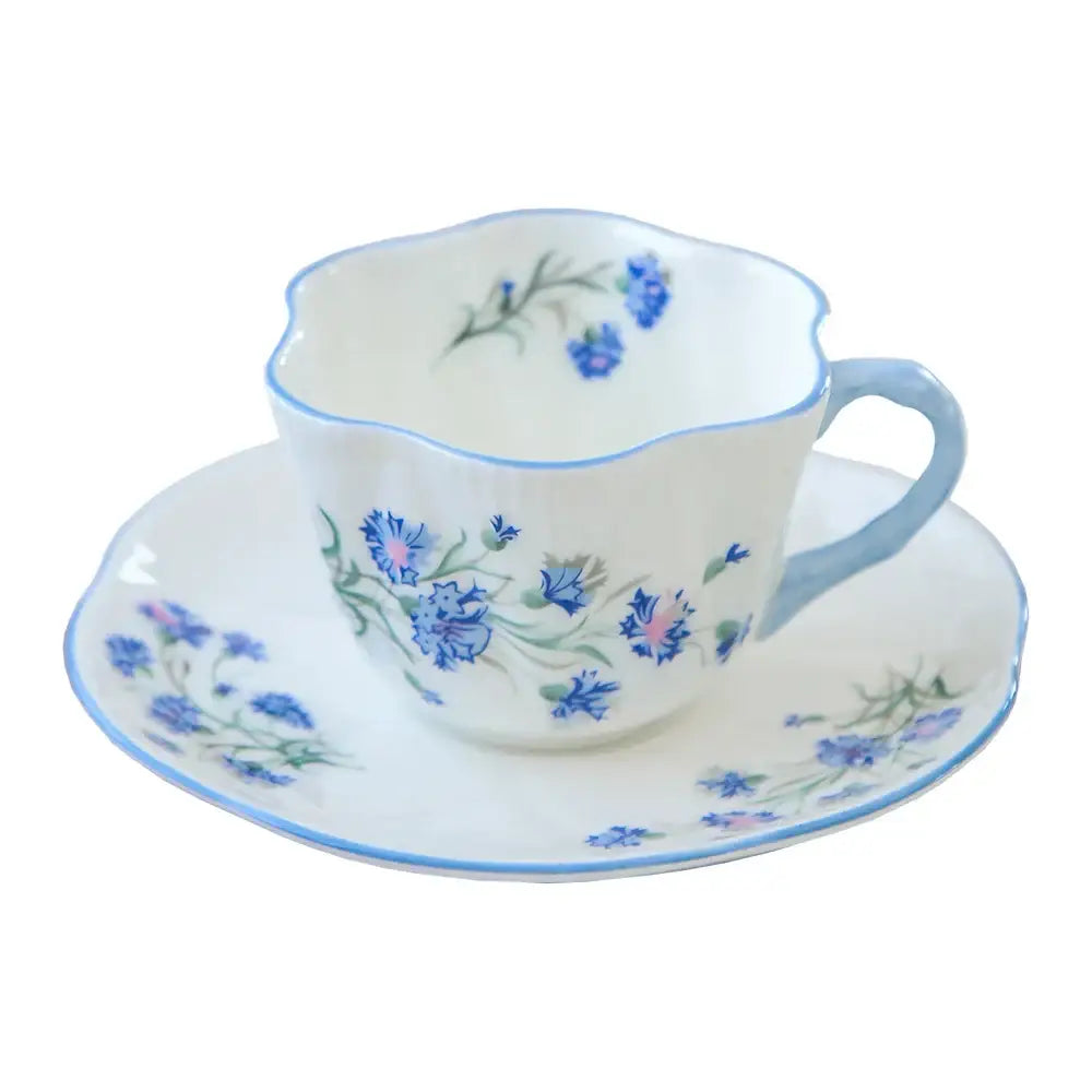 A delicate white porcelain coffee cup and saucer set with blue cornflower floral pattern from decorbites bone collection