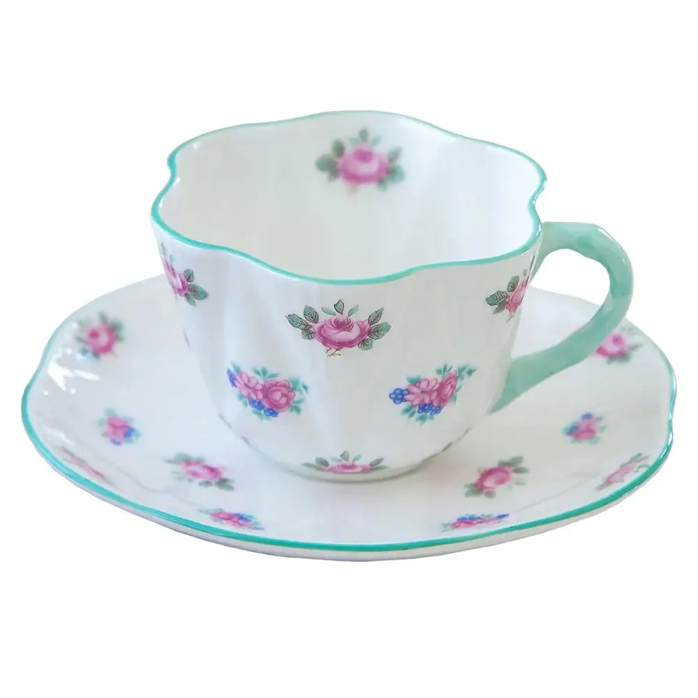 A delicate white bone decorbites coffee cup and saucer set with pink roses and mint-green accents for dining room decor