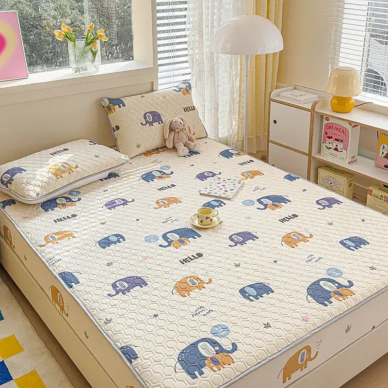 Cream-colored quilted bed pad with playful blue purple and orange elephants and hello text in fitted sheet set