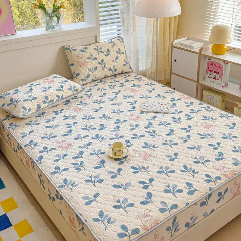 Pastel floral quilted latex fitted sheet set with cream base, blue and pink botanical motifs, and subtle honeycomb texture
