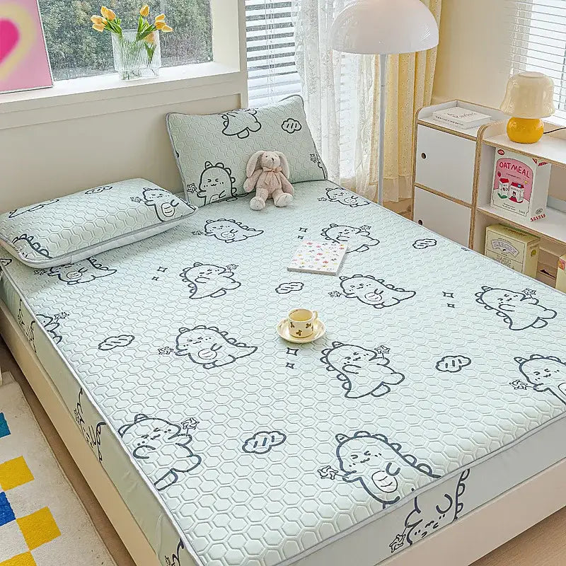 Pastel floral quilted latex fitted sheet set with light green quilted bed pad featuring black cartoon dinosaurs and clouds
