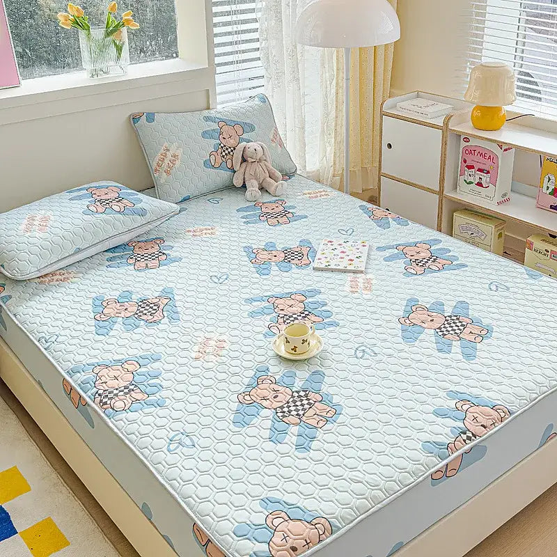 Light blue quilted bed pad with cartoon bears and hexagonal texture in a pastel floral quilted latex fitted sheet set