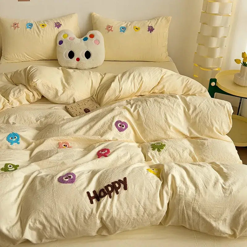 Cream-colored plush bedding set with colorful decorbites cartoon embroidery and brown happy word detailing