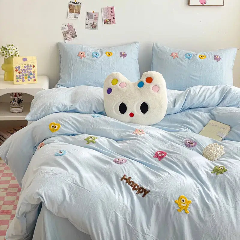 Pastel green cartoon embroidery bedding set with light blue quilted comforter featuring happy monsters and plush cat pillow