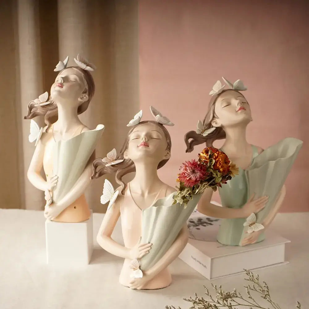 Three elegant pastel green and peach butterfly girl vase statues with floral arrangements and delicate white butterfly accents