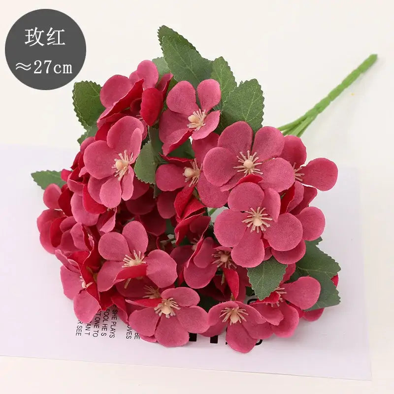 A bouquet of artificial pink cherry blossoms with green leaves featuring dry flower embossing for living room decor