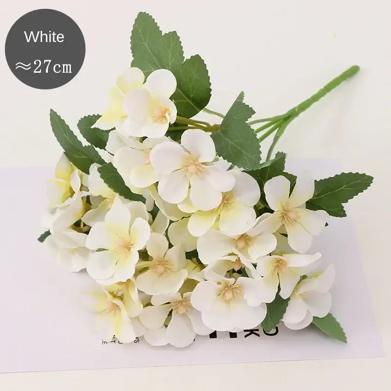 A cluster of white artificial pastel hydrangea begonia flower dry with delicate petals and green stems for decor