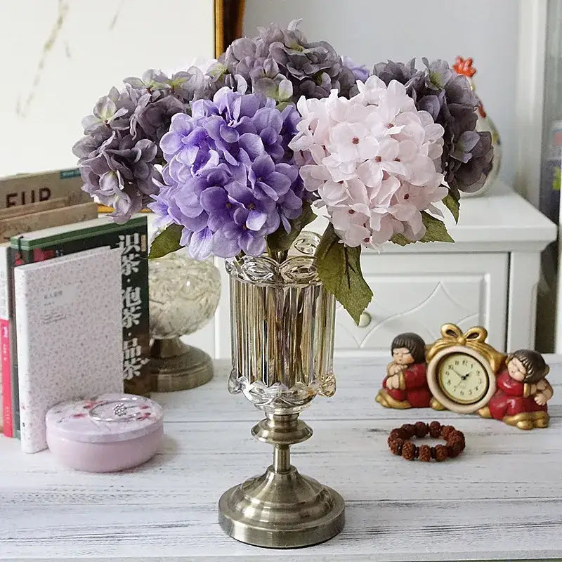 A decorbites hydrangea branch silk flower bouquet in pastel purple and pink arranged in an ornate silver vase for dining room decor