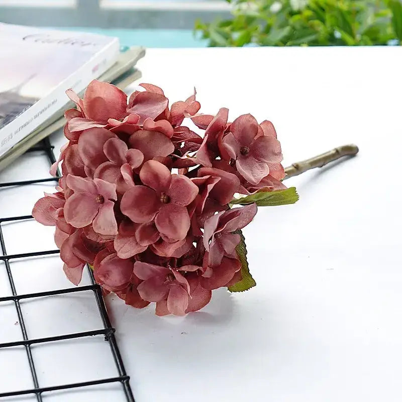 A cluster of burgundy pastel hydrangea branch silk flowers with layered petals on a slender brown stem for decorbites hydrangea branch decor