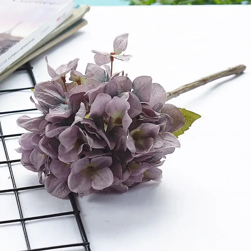 A pastel purple decorbites hydrangea branch silk flower bouquet with layered petals and slender brown stem for dining room decor