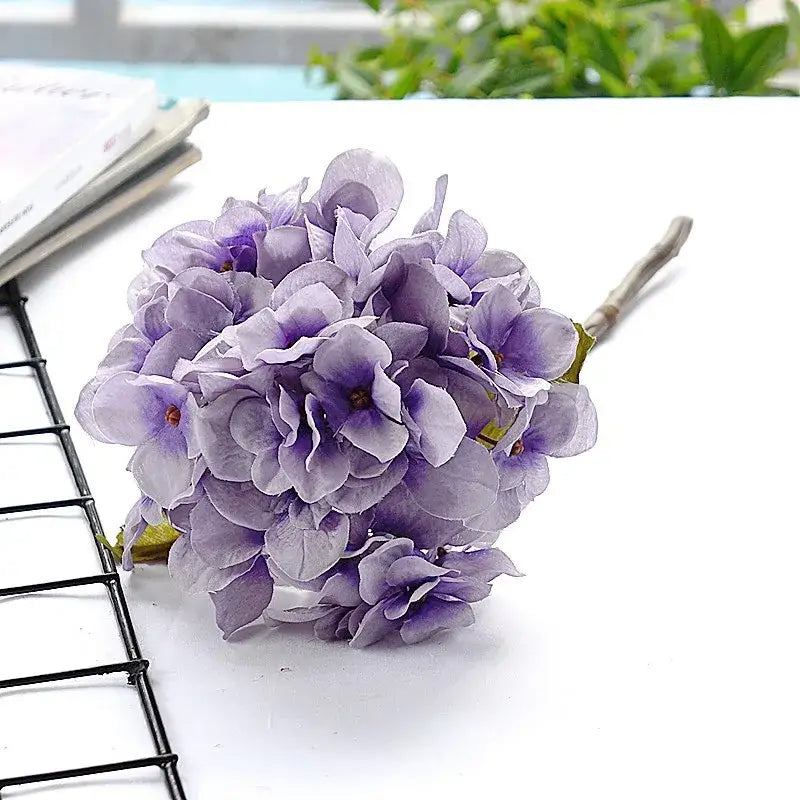 A cluster of artificial purple pastel hydrangea branch silk flowers with layered petals for decorbites dining room decor