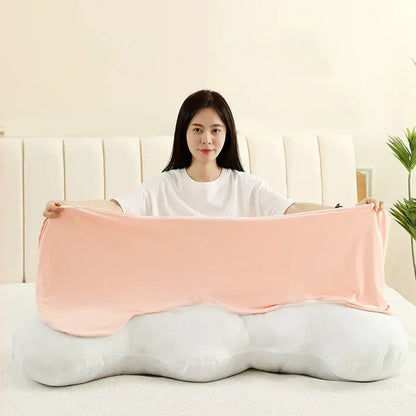 A pastel ice cream wavy plush pillow in blush pink satin-like fabric draped over a white cloud-shaped decorbites ice cream pillow