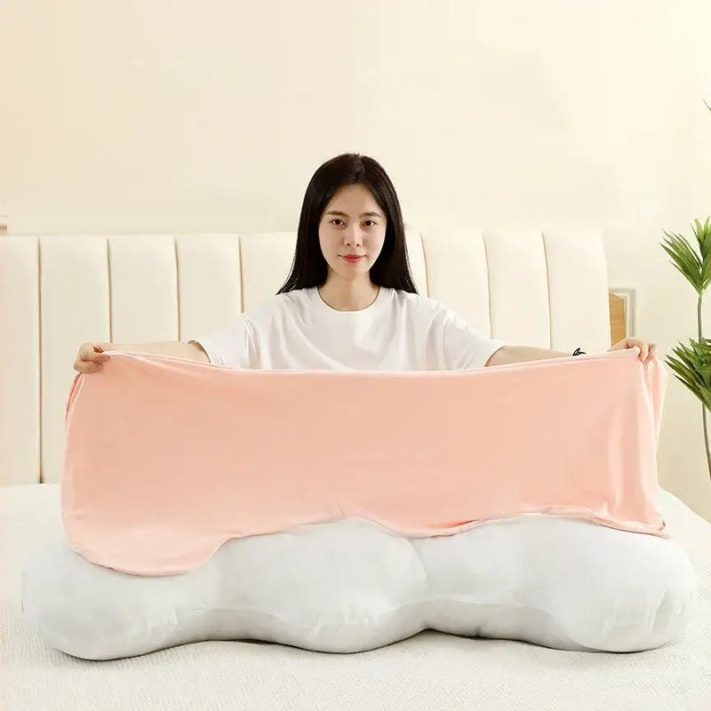 A pastel ice cream wavy plush pillow in blush pink satin-like fabric draped over a white cloud-shaped decorbites ice cream pillow