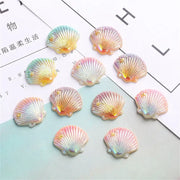 Pastel iridescent seashell-shaped resin charms in pink peach and mint with gold stars for colorful pearl shells decor