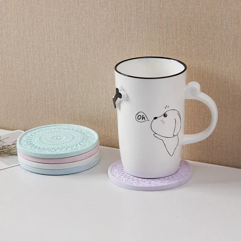 A stack of pastel mandala patterned decorbites diatomite round coasters with a lavender one holding a white ceramic mug