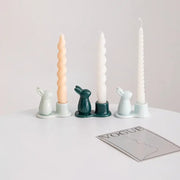 Pastel multi color bunny rabbit ceramic candle holders in green teal and blue each holding a tall twisted wax candle