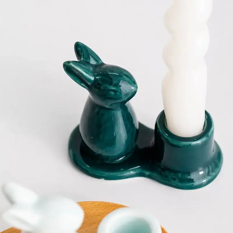 Deep green bunny rabbit ceramic candle holder with integrated socket holding white twisted candle for dining room