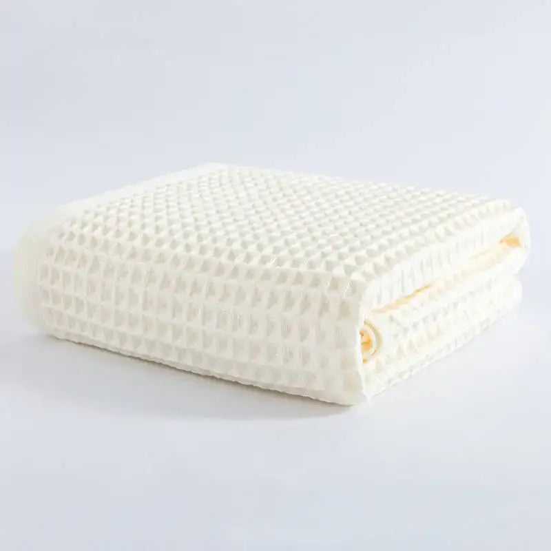A neatly folded cream-colored decorbites cotton waffle bath towel with a soft textured surface for bathroom use