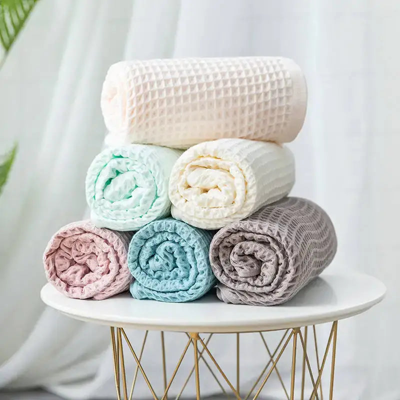 A stack of pastel multi color decorbites cotton waffle bath towels in pink mint green cream and gray for bathroom use